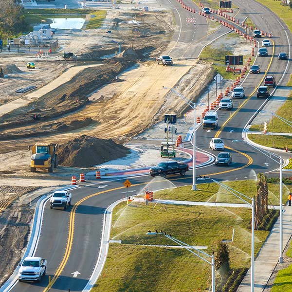 Cars driving on road next to construction